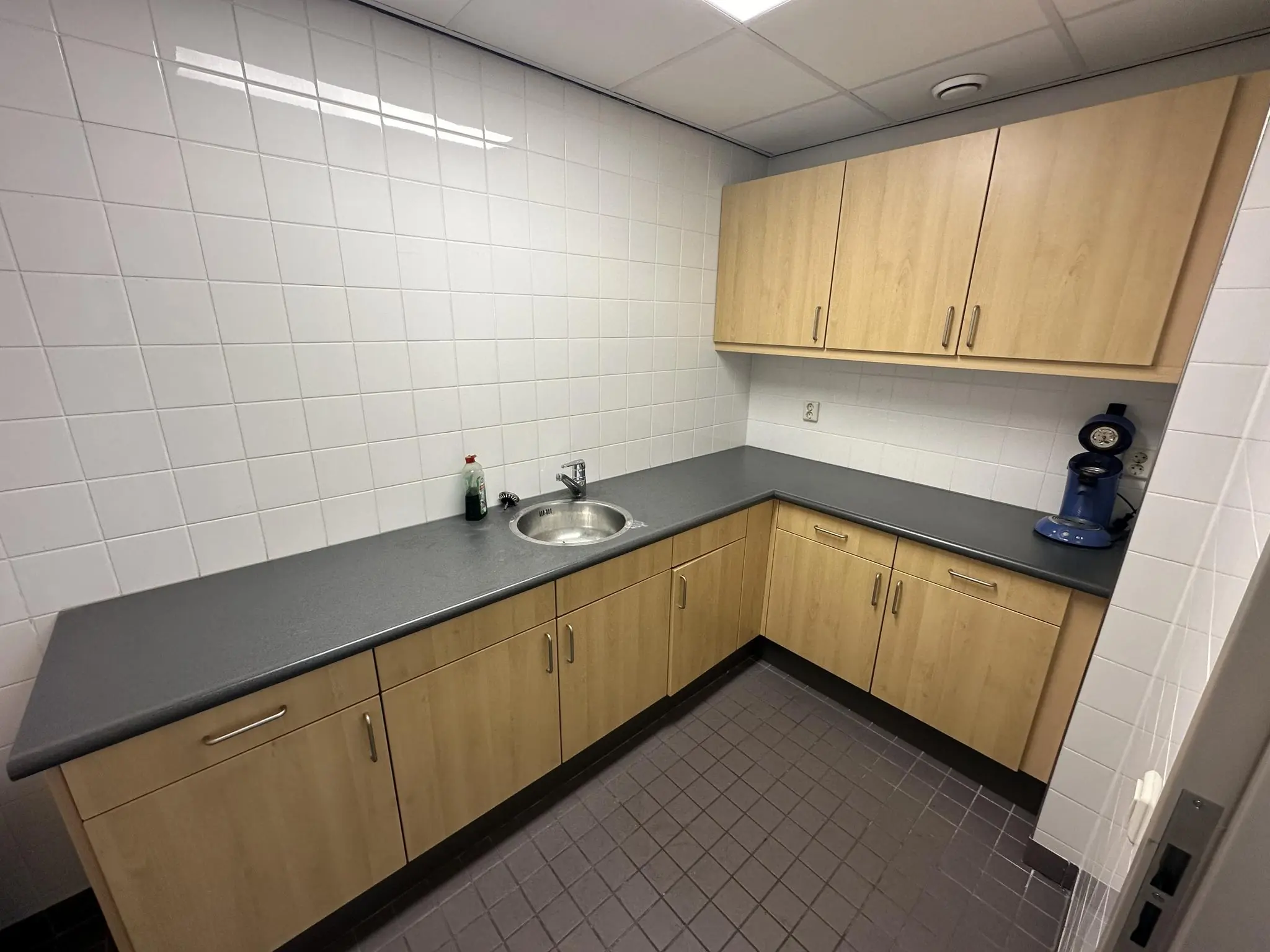 Keukenhoek met licht houten kastjes, een donker aanrechtblad, spoelbak en een koffiezetapparaat in een ruimte aan de Van der Hagenstraat.